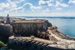 photo of a El Morro Fort, an old fortress with thick stone walls and a lighthouse, beside the ocean
