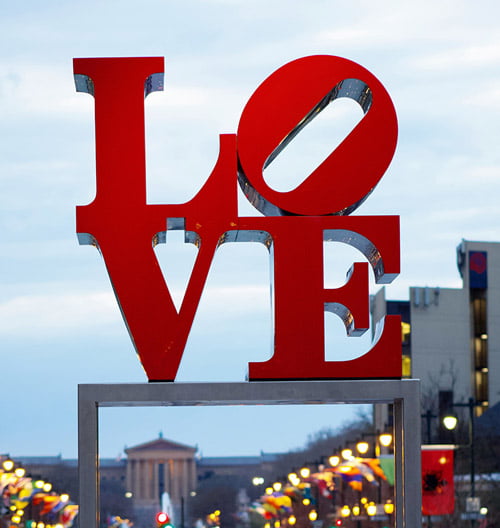 photo of public art piece LOVE statue, the red letters L O V E arranged in a square, with the O slanted to the right.